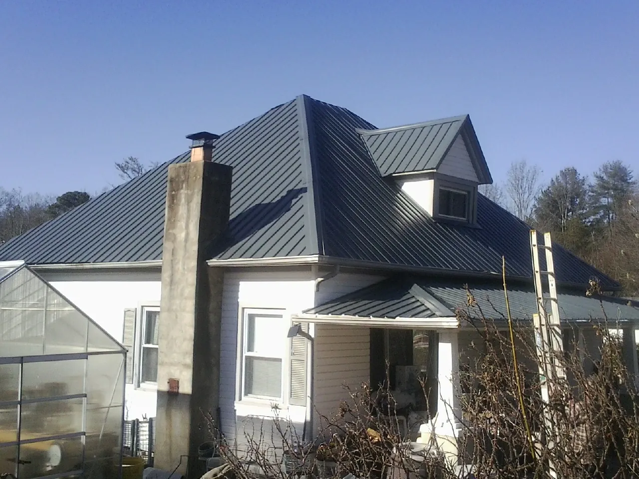 Dark blue standing seam metal roof on a white farmhouse with dormer — Slate & Tile Roof Repair by Roofing Brothers in Hunt