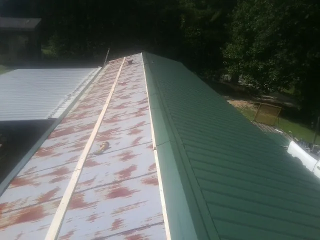 Old rusted panels beside newly installed green metal roofing — Wind Damage Roof Repair by Roofing Brothers in Hunt