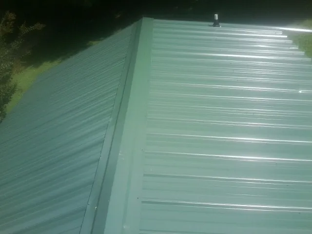 New green metal panels meeting at the ridge of a roof — Flat Roof Repair work by our crew in Hunt