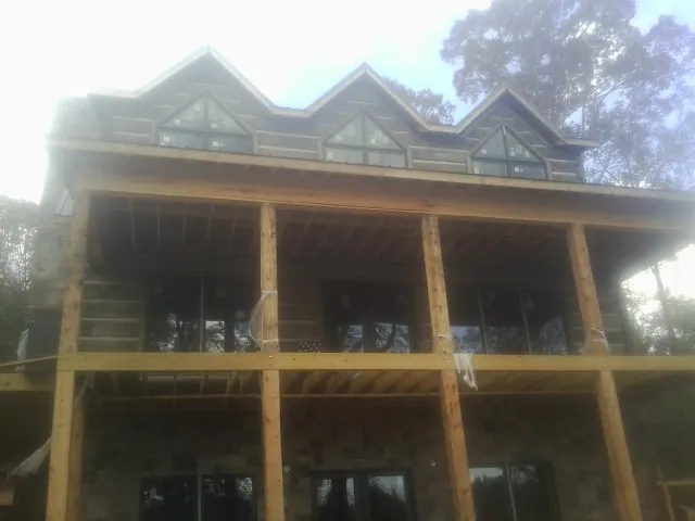 Dormers and porch framing on a large log home under construction — Roof Coating work by our crew in Hunt