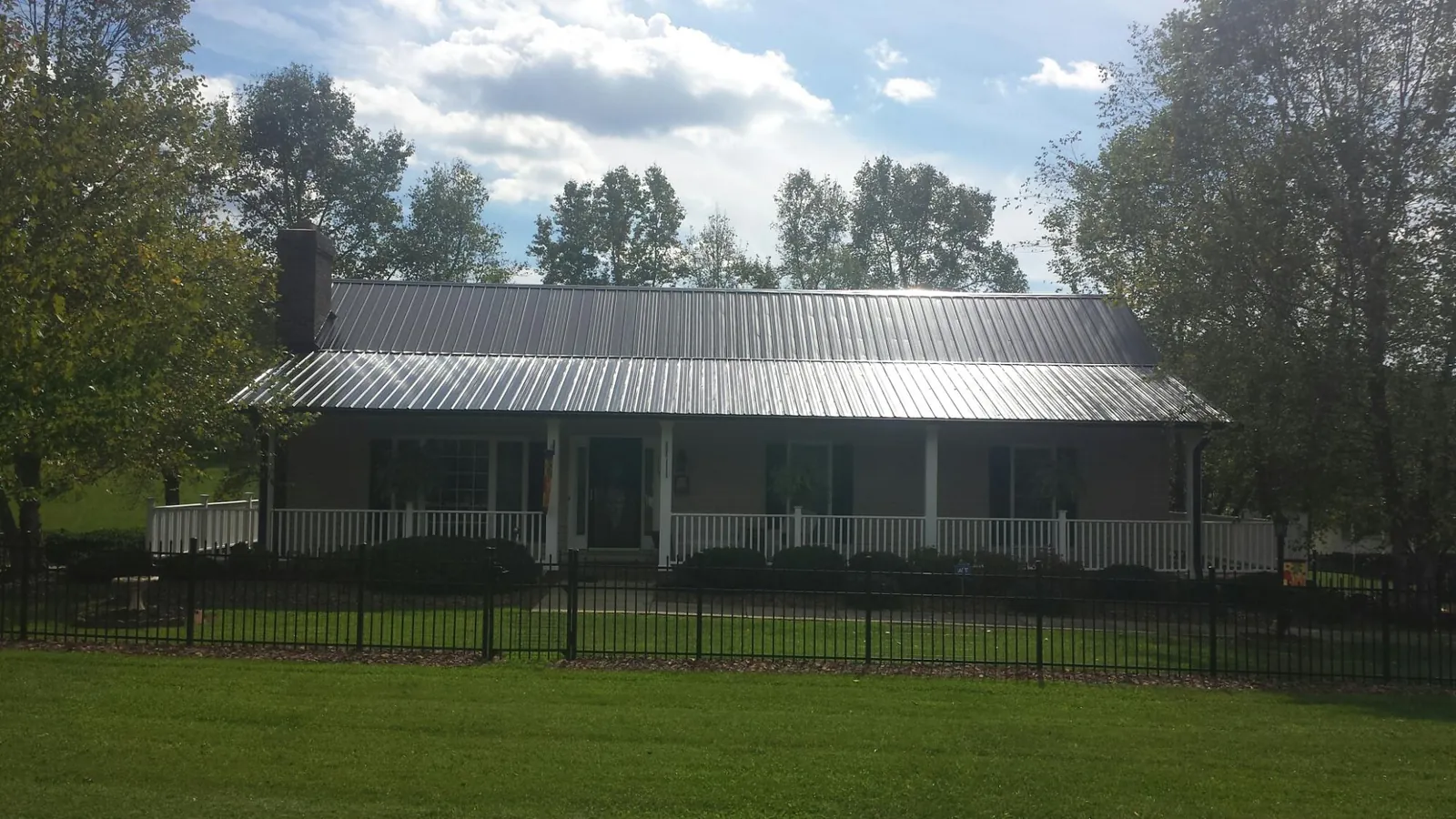 Gray metal roof on a brick ranch with a full width front porch — Gutter Guard Installation work by our crew in Hunt