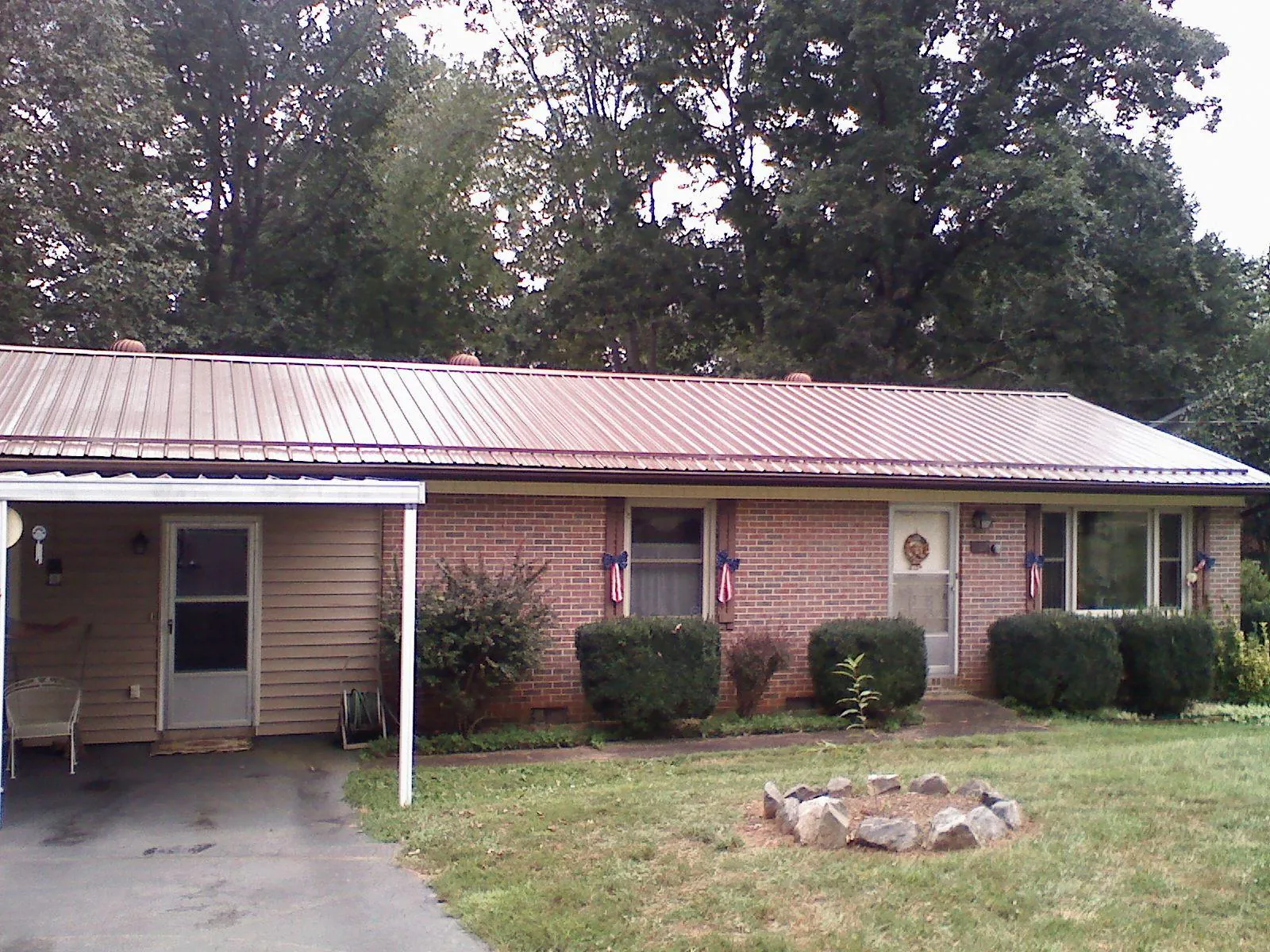 Bronze metal roof and carport on a brick ranch home — Roof Repair work by our crew in Hunt