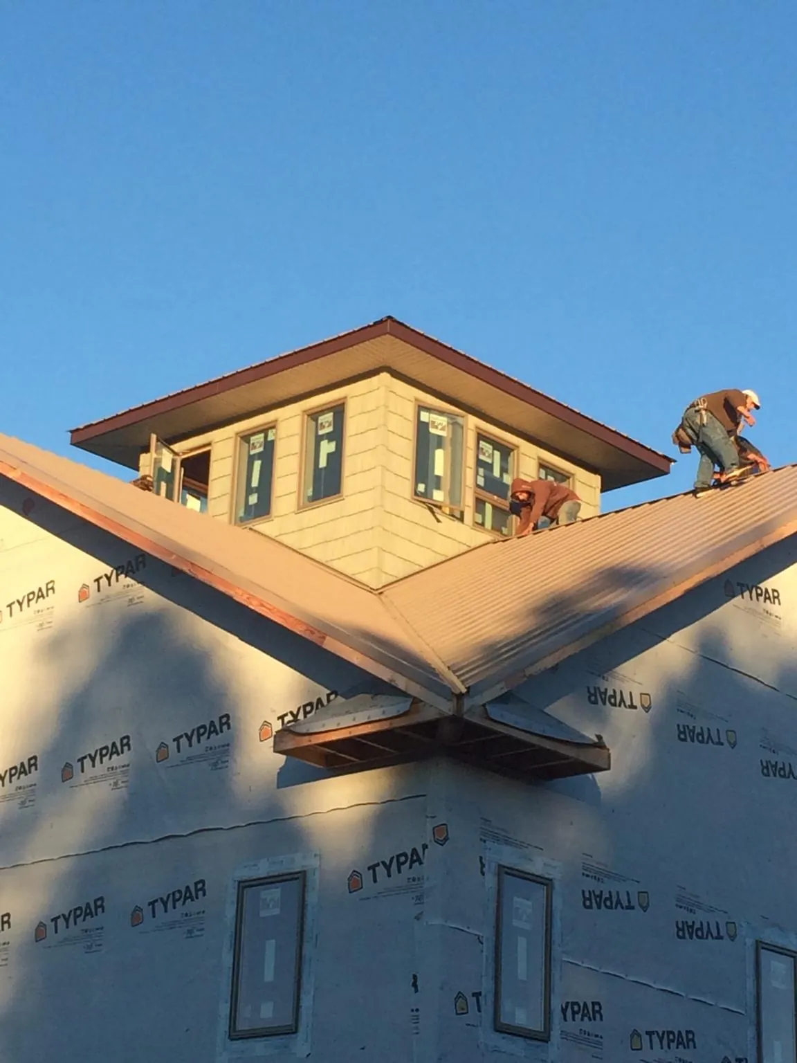 Roofers working around a rooftop cupola on a new metal roof at sunset — Roof Waterproofing in Hunt by Roofing Brothers